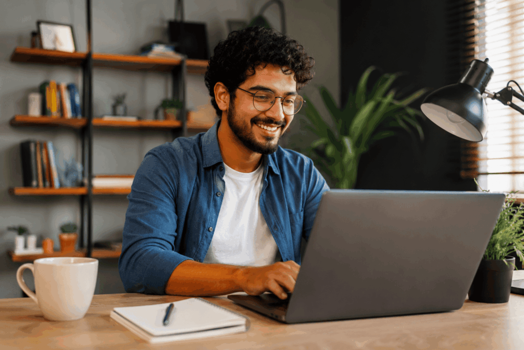 A imagem mostra um profissional trabalhando concentrado em seu notebook, em um ambiente de home office moderno e acolhedor. O espaço transmite tecnologia, organização e criatividade, elementos associados à rotina de quem atua com desenvolvimento de software. A composição humaniza a profissão e representa a possibilidade de trabalho remoto na área de tecnologia.